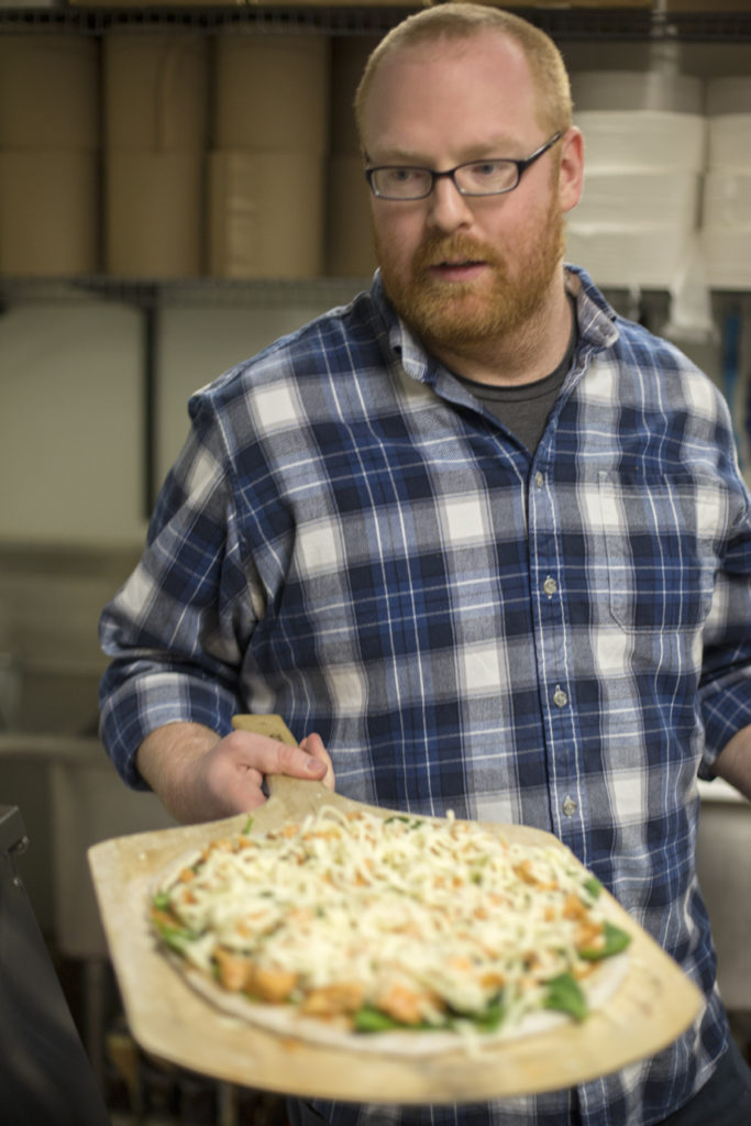 Alumnus Jon Leek puts a pizza pie into an oven at Orbit Pinball Lounge. His company, Pulse Pizza serves pizzas made with spent beer grains out of the Maplewood, Missouri, bar on Monday and Thursday nights.
