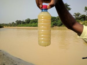 A member of Kenneth Bansah's research team holds a bottle of dirty water taken from the polluted Tano River. Kenneth Bansah.