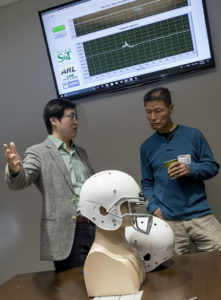 Dr. Jie Huang, assistant professor of electrical and computer engineering at Missouri S&T, demonstrates helmets he’s made with fiber optic sensors to Dr Chiming Huang, associate professor of biological sciences at the University of Missouri-Kansas City, during a recent traumatic brain injury research conclave at the Army base in Fort Leonard Wood, Missouri. Photo by Tom Wagner/Missouri S&T, ©2019 Missouri S&T