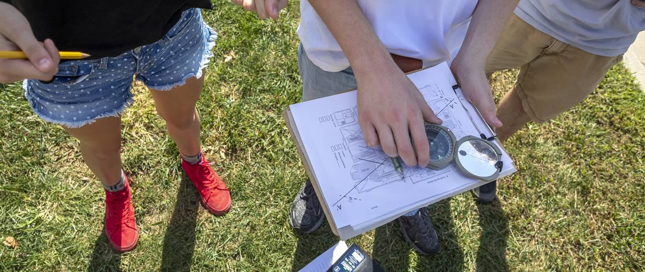 Students using a compass during class on campus