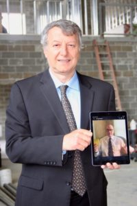 Dr. Khayat holding iPad photo of Dr. Poston giving a thumbs-up in a socially distanced award presentation