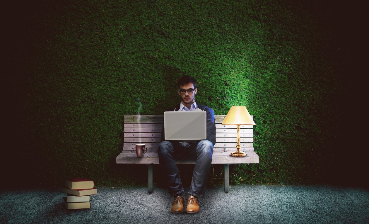 Photo of man working on laptop by lamp light