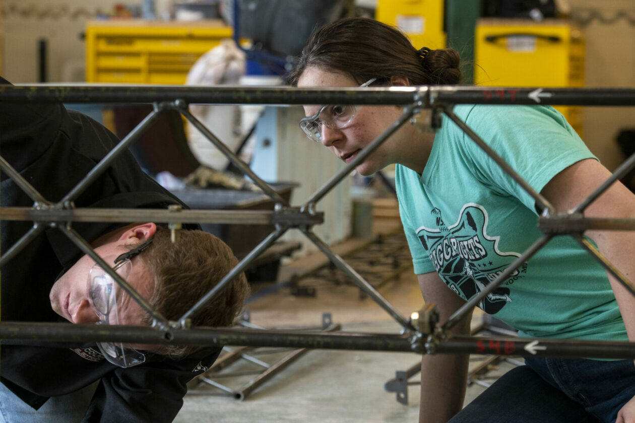 Photo of students working on segment of steel bridge model