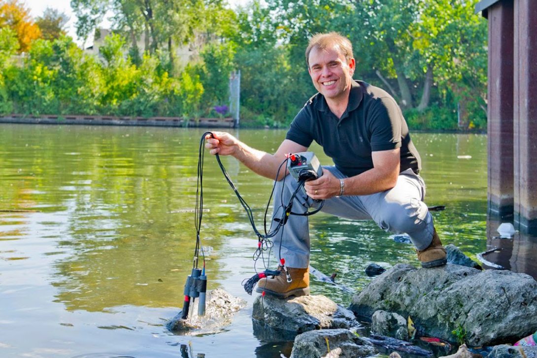 Man at water's edge with water-testing equipment