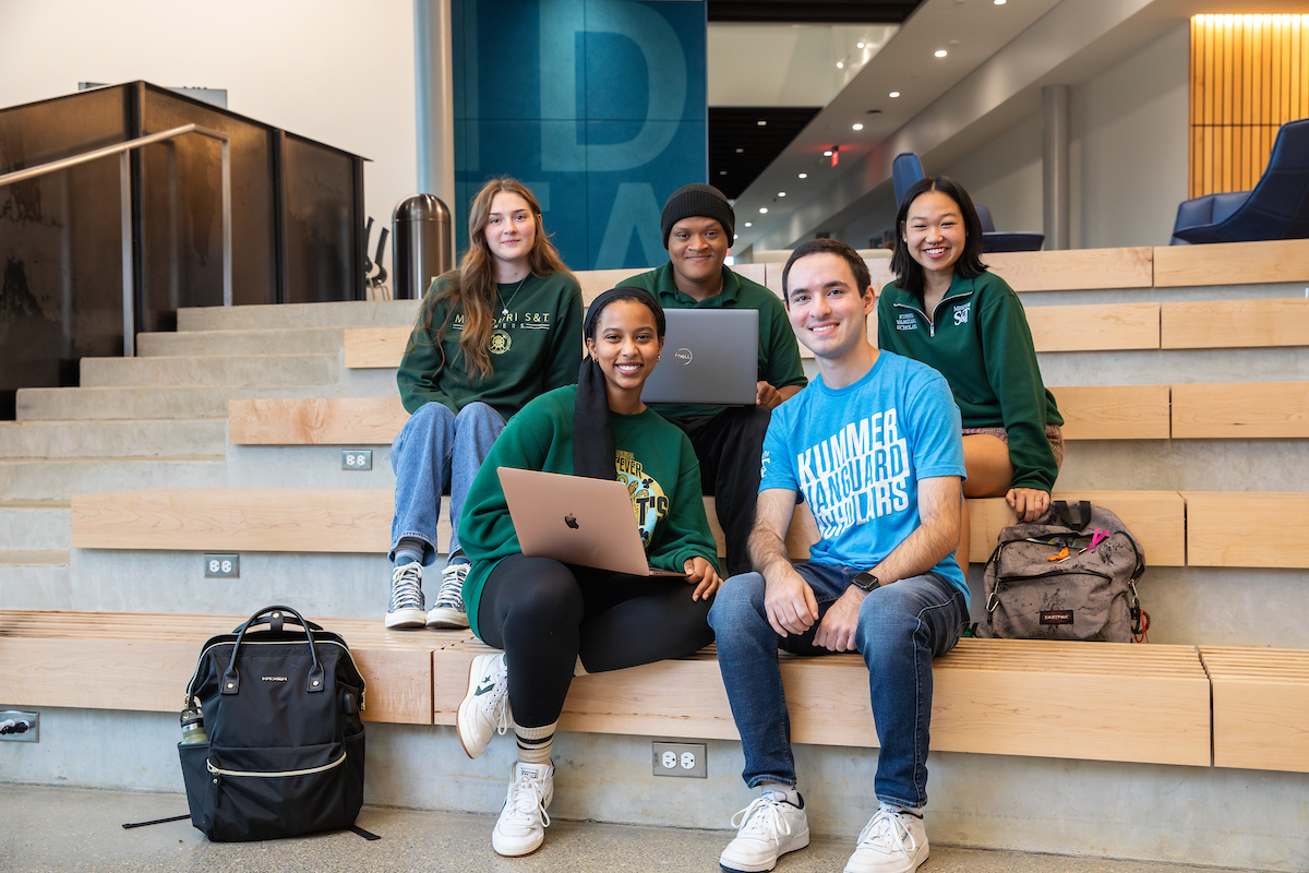 Five Kummer Vanguard Scholars sit on steps inside Innovation Lab atrium