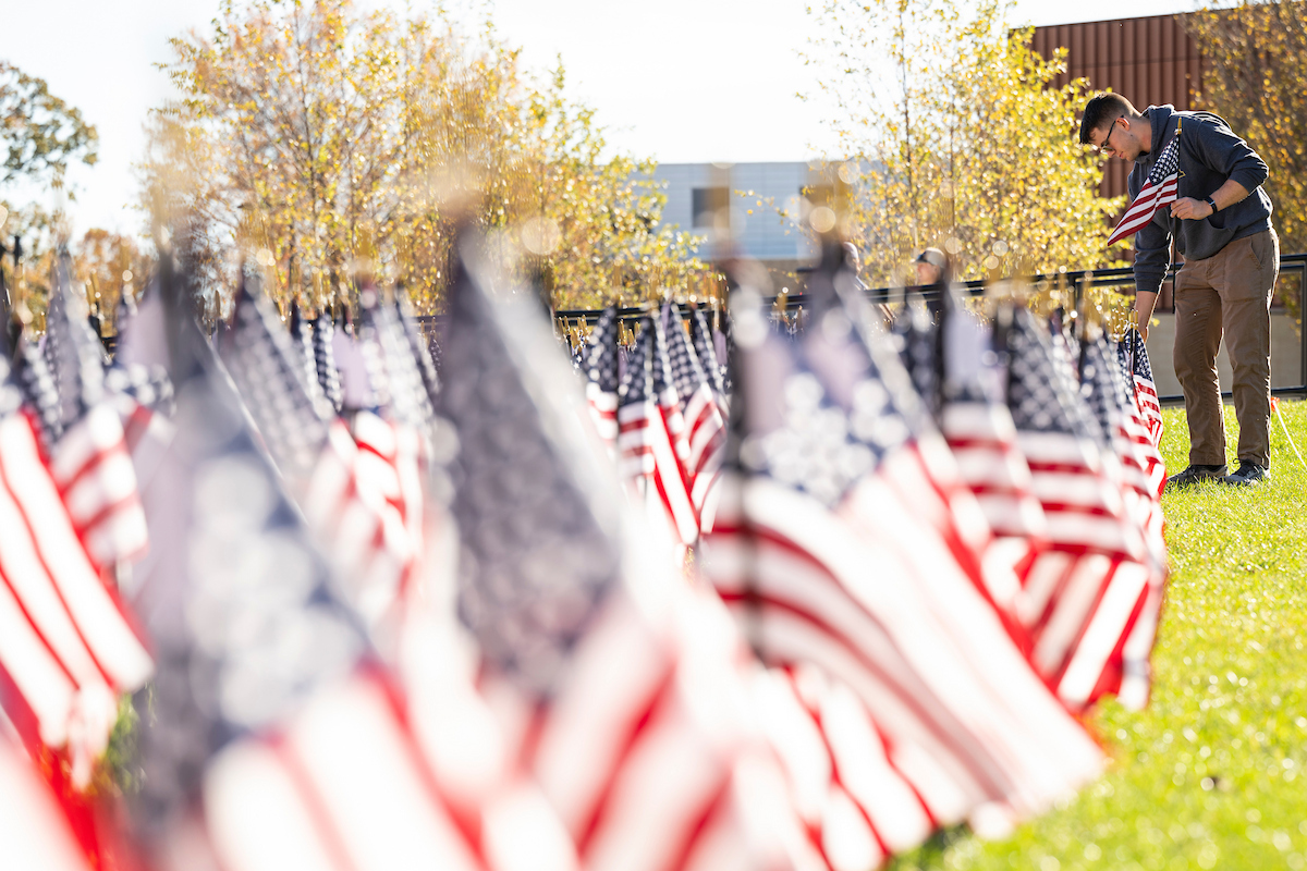 Carter Rhoades, U.S. Army veteran and sophomore in chemical engineering, places flags on the Havener Center lawn on Veterans' Day.