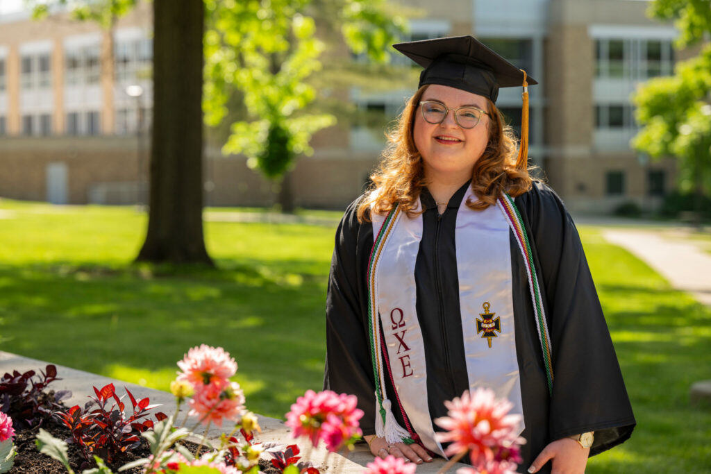 Woman in graduation regalia outside Butler-Carlton Civil Engineering Hall. 