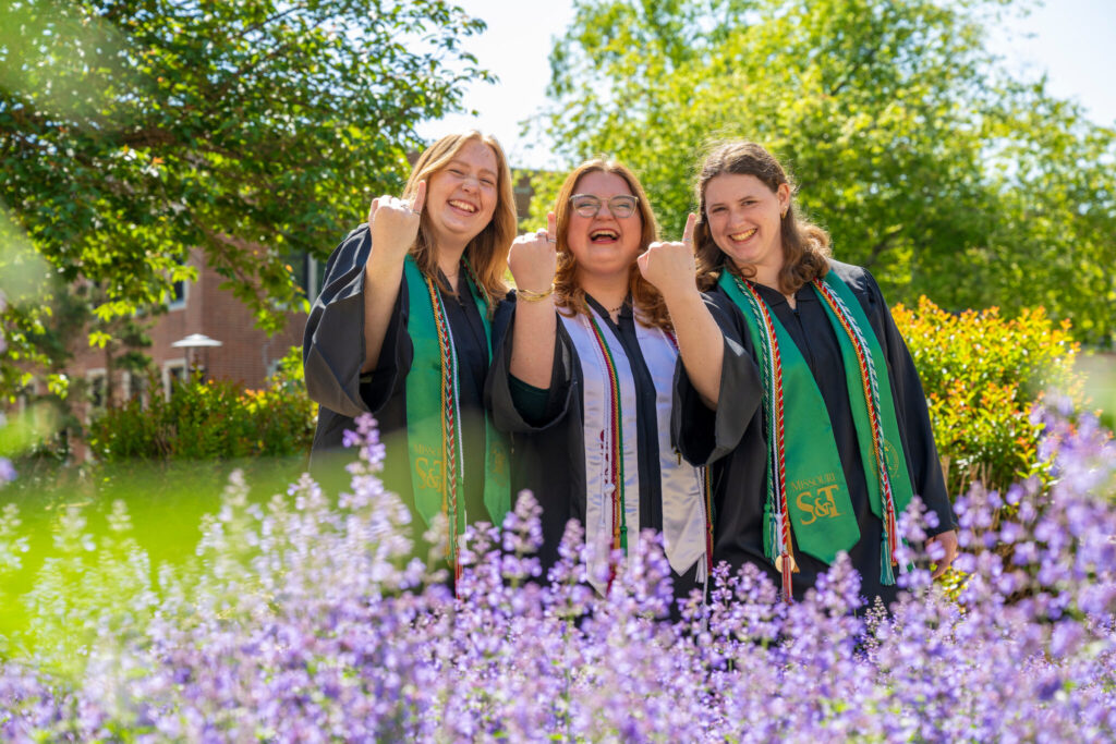 Three graduates show off Order of Engineer rings. 