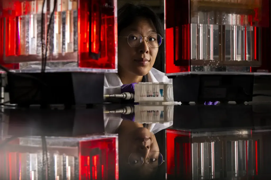 Face of researcher visible among chemistry lab equipment with a reflection in research bench