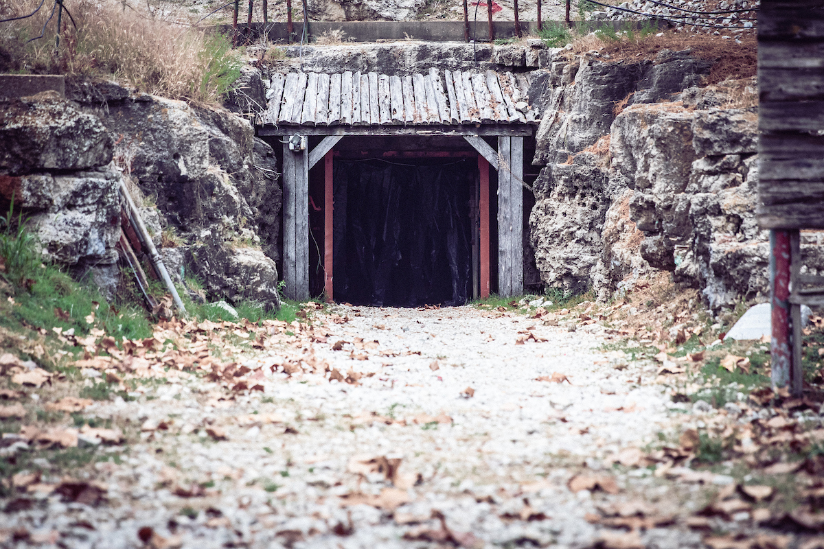 The dark entryway of the Experimental Mine at Missouri S&T, set into a rocky hillside at the end of a path.